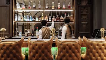 A bar area with leather chairs, a bar counter, and a variety of liquor bottles.