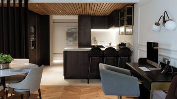 A modern kitchen with a central island, dark cabinetry, and a dining area with a round table and chairs.