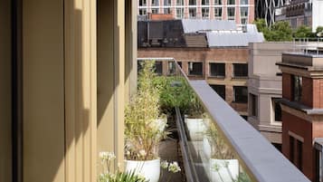 Un balcón con plantas en macetas y vistas de edificios modernos.