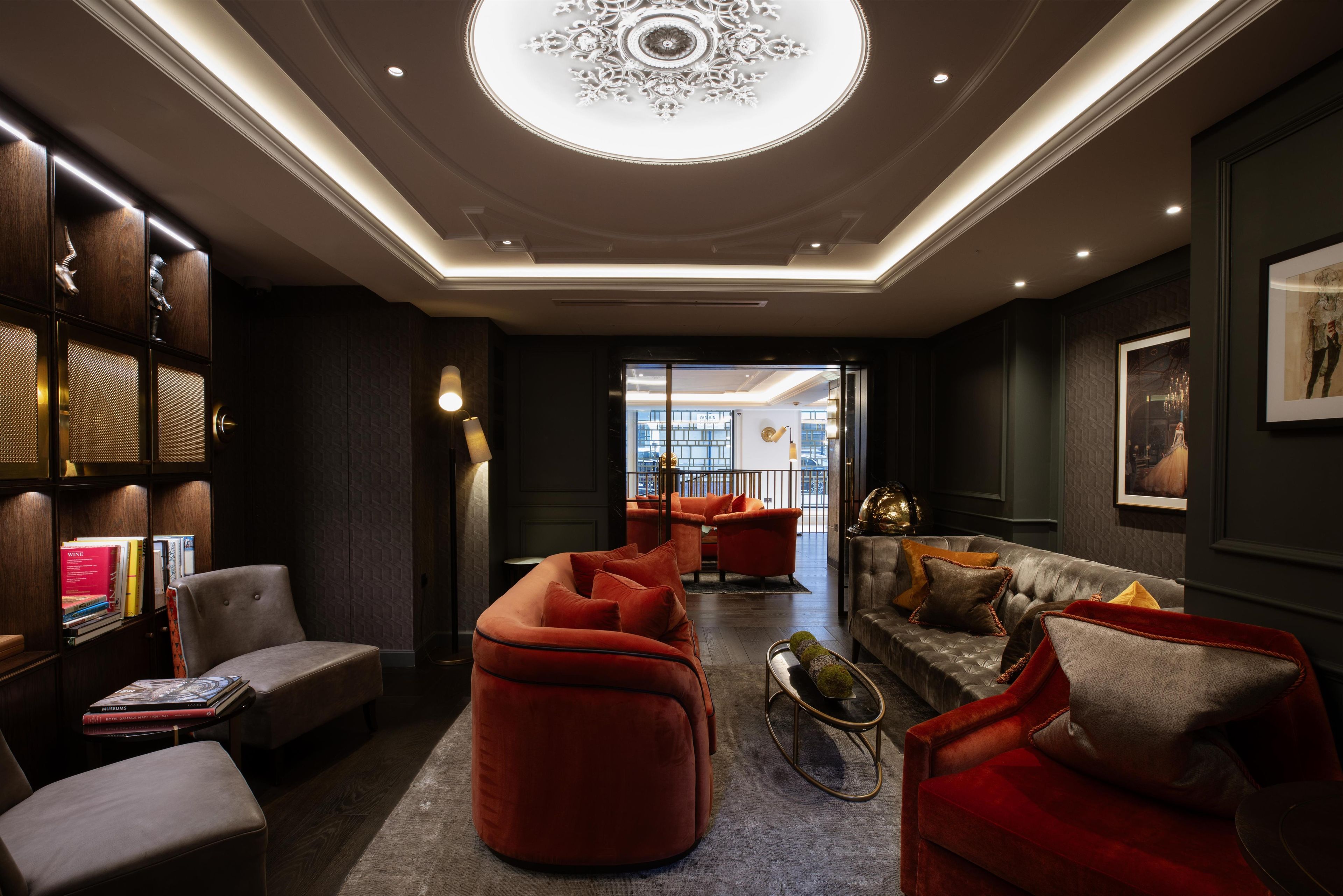 Un interior moderno con una zona de estar central, un techo decorativo y vistas a un espacio exterior.