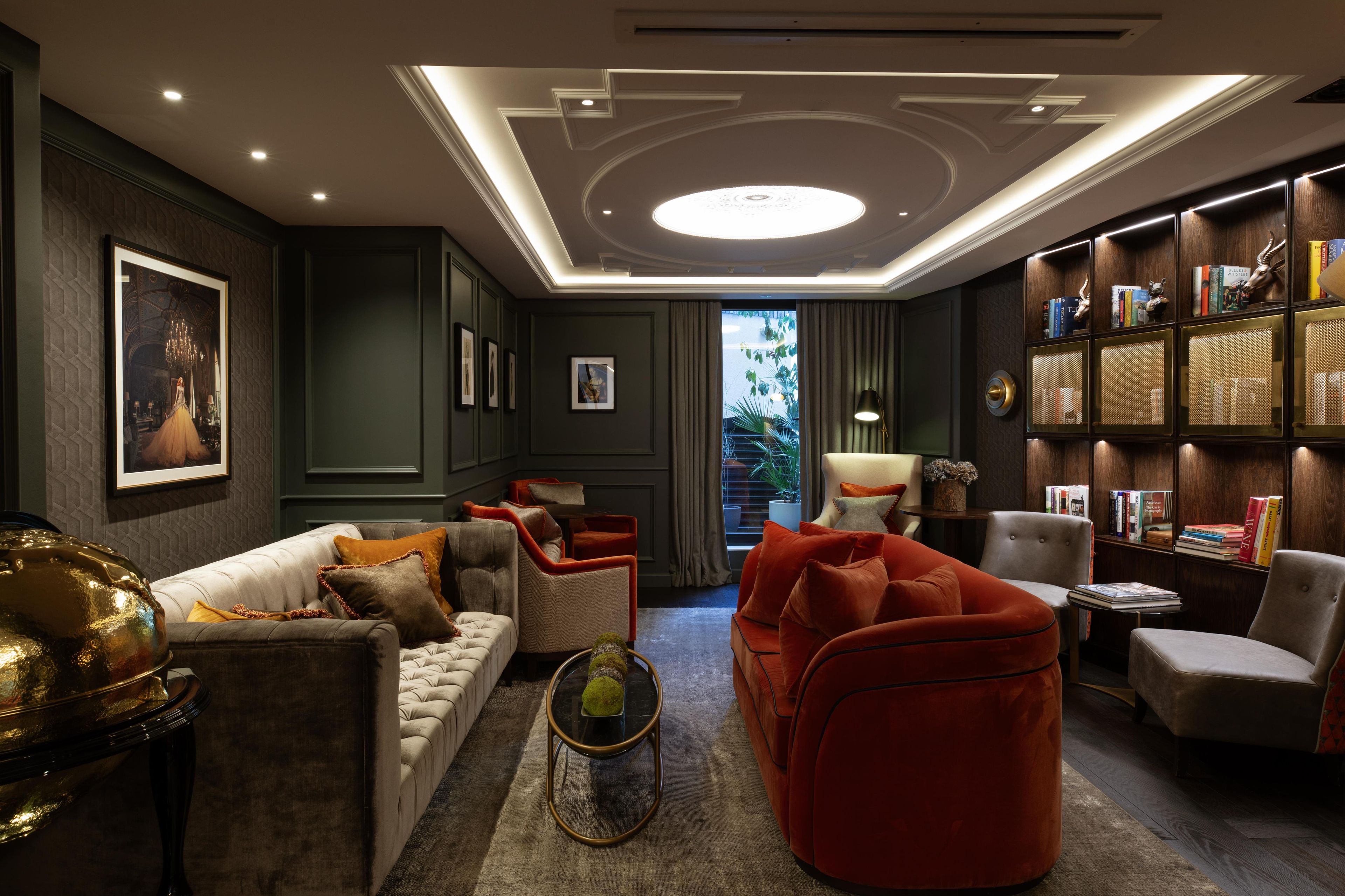 A modern living room with a sofa, armchairs, a coffee table, and a bookshelf.
