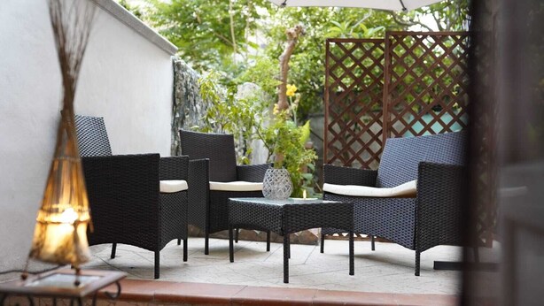 Une terrasse extérieure aménagée avec des meubles en osier, une table et un vase décoratif.