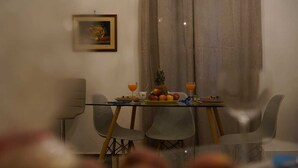 Un coin repas avec une table en verre, des chaises et une assiette de fruits.