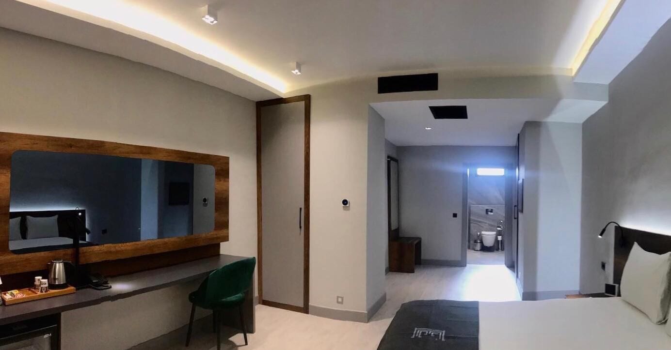 Una habitación de hotel moderna con un espejo grande, un escritorio con silla, una cama y un vestidor.