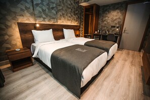 A hotel room with two beds, a wooden headboard, a desk, and a wardrobe. - Emens Hotel (Izmir)