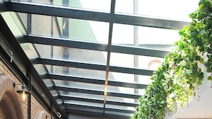 A restaurant with a brick wall, green velvet chairs, and a glass ceiling. - Emens Hotel (Izmir)