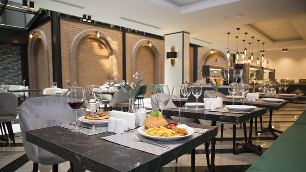 Comedor con mesas dispuestas para comer, con platos de comida y copas de vino.