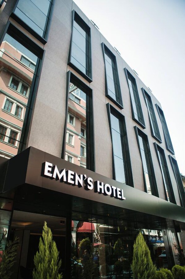 Un edificio moderno de hotel con un letrero llamativo que dice "EMEN'S HOTEL".