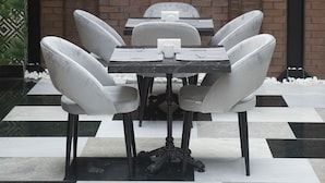 A brick wall with an arched doorway, a table with six chairs, and a hanging light fixture. - Emens Hotel (Izmir)