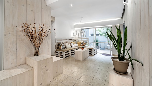 Una sala de estar moderna con un sofá seccional de madera, una mesa de centro y una planta en maceta.