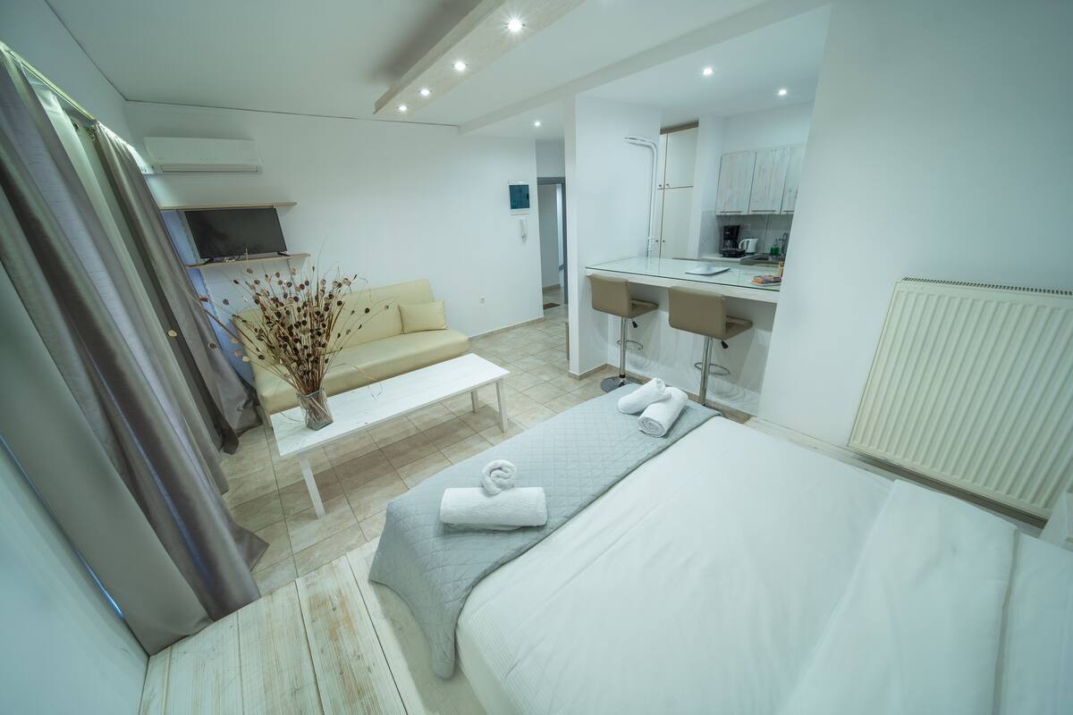 Une chambre d’hôtel moderne équipée d’un lit, d’un canapé, d’une petite table et d’un coin cuisine.