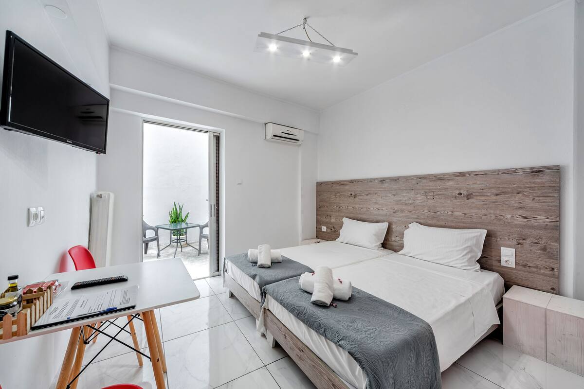 Une chambre d’hôtel moderne, dotée d’un grand lit, d’un bureau avec un ordinateur et d’un téléviseur fixé au mur.