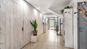 Un pasillo moderno con paneles de madera, una planta en maceta y piso de baldosas.
