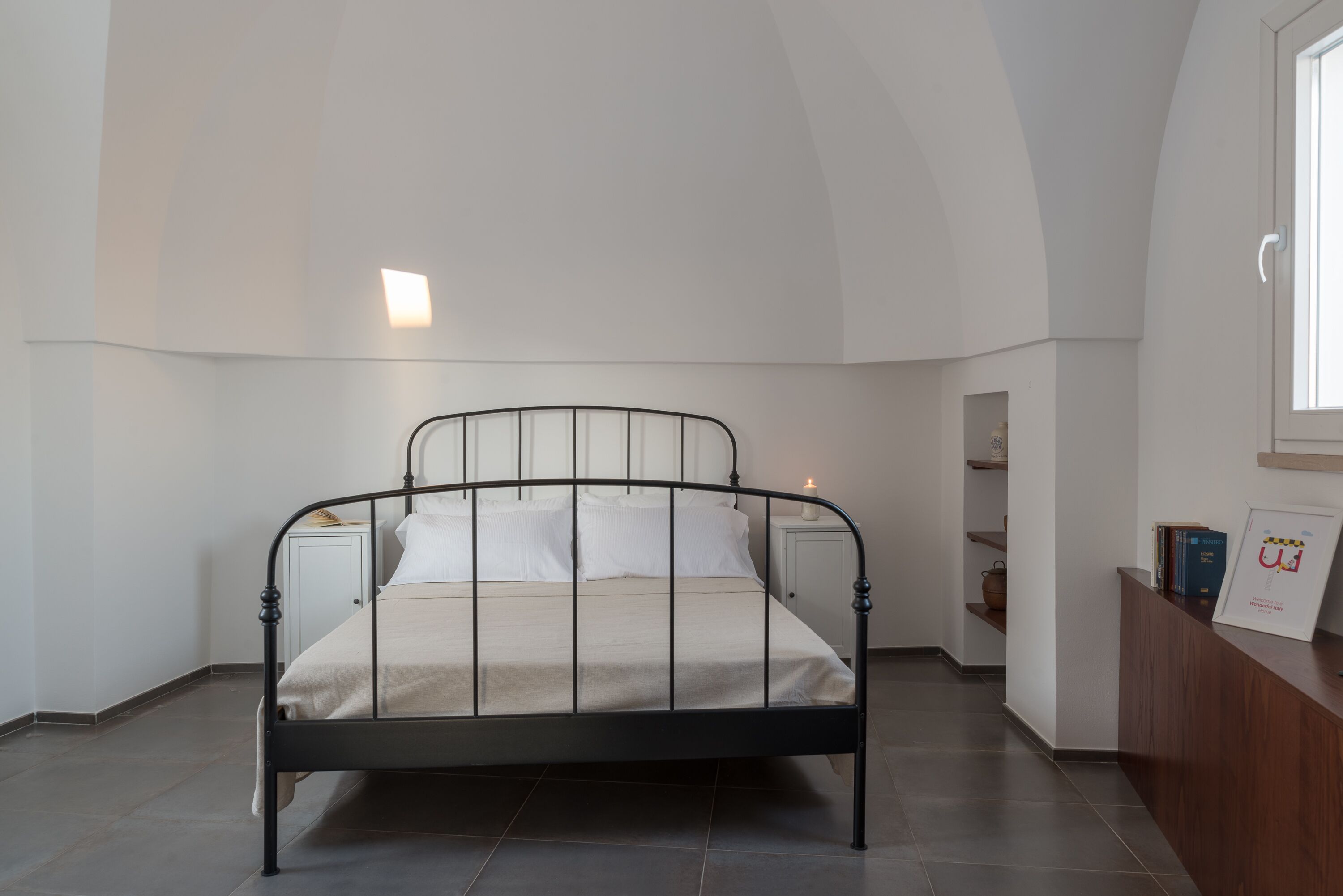 Un dormitorio con cama, mesita de noche, escritorio y ventana.