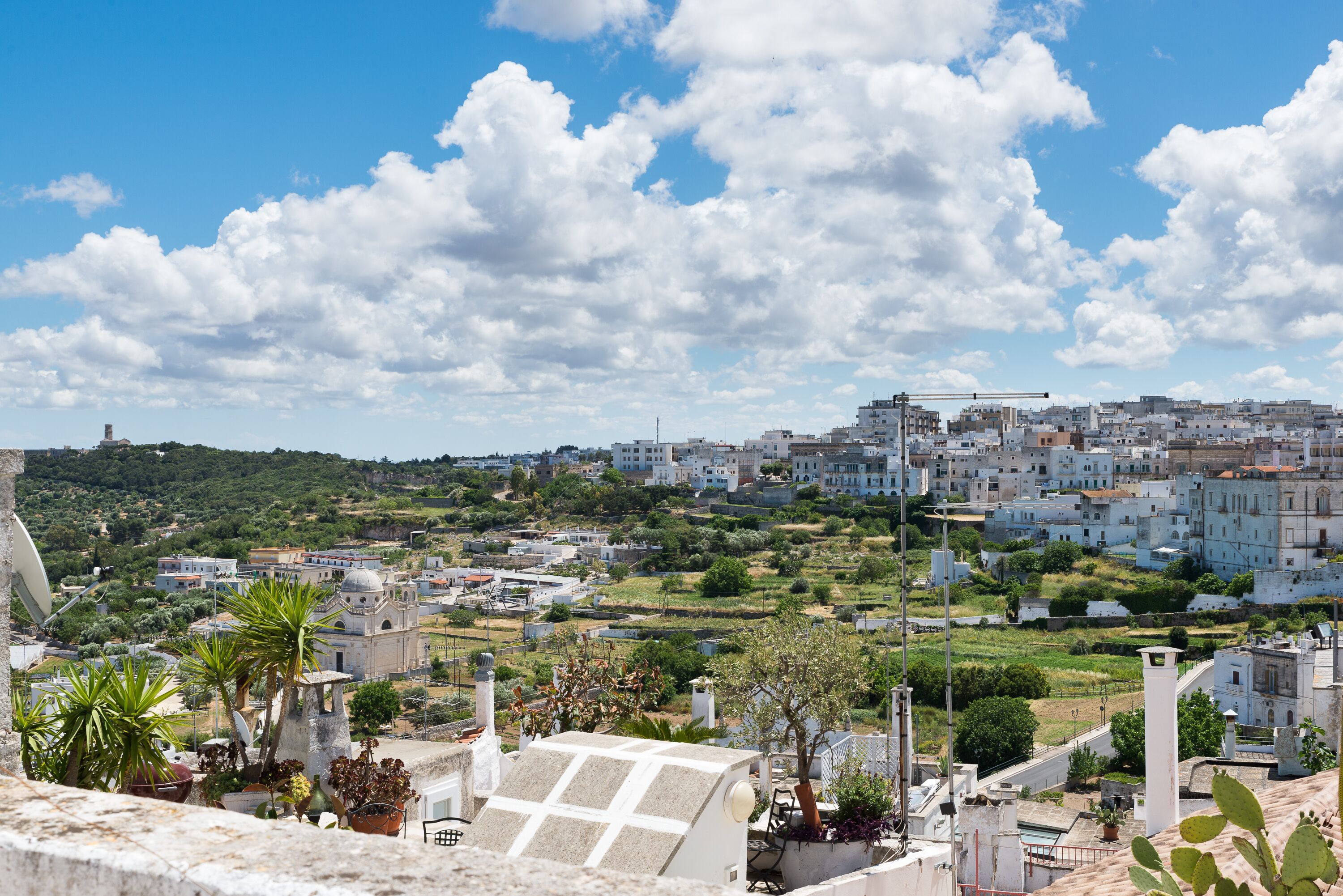 A residential area with a mix of modern and traditional buildings, a clear sky, and some greenery.