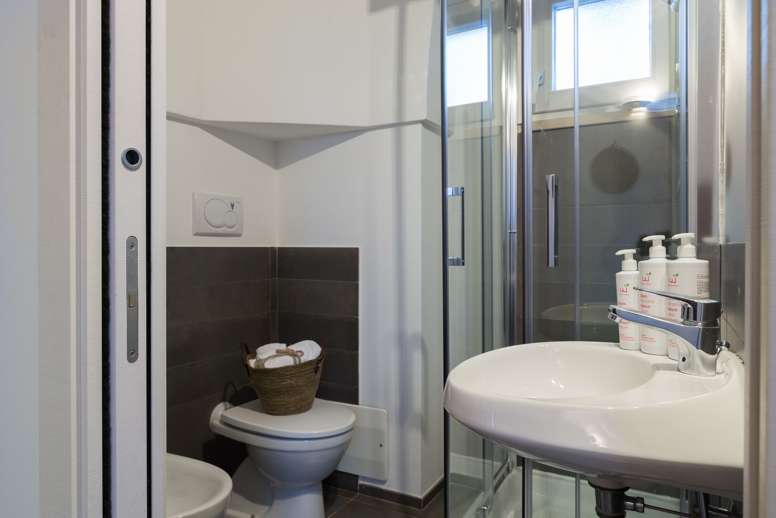 A modern bathroom with a glass shower enclosure, a white sink, and a toilet.