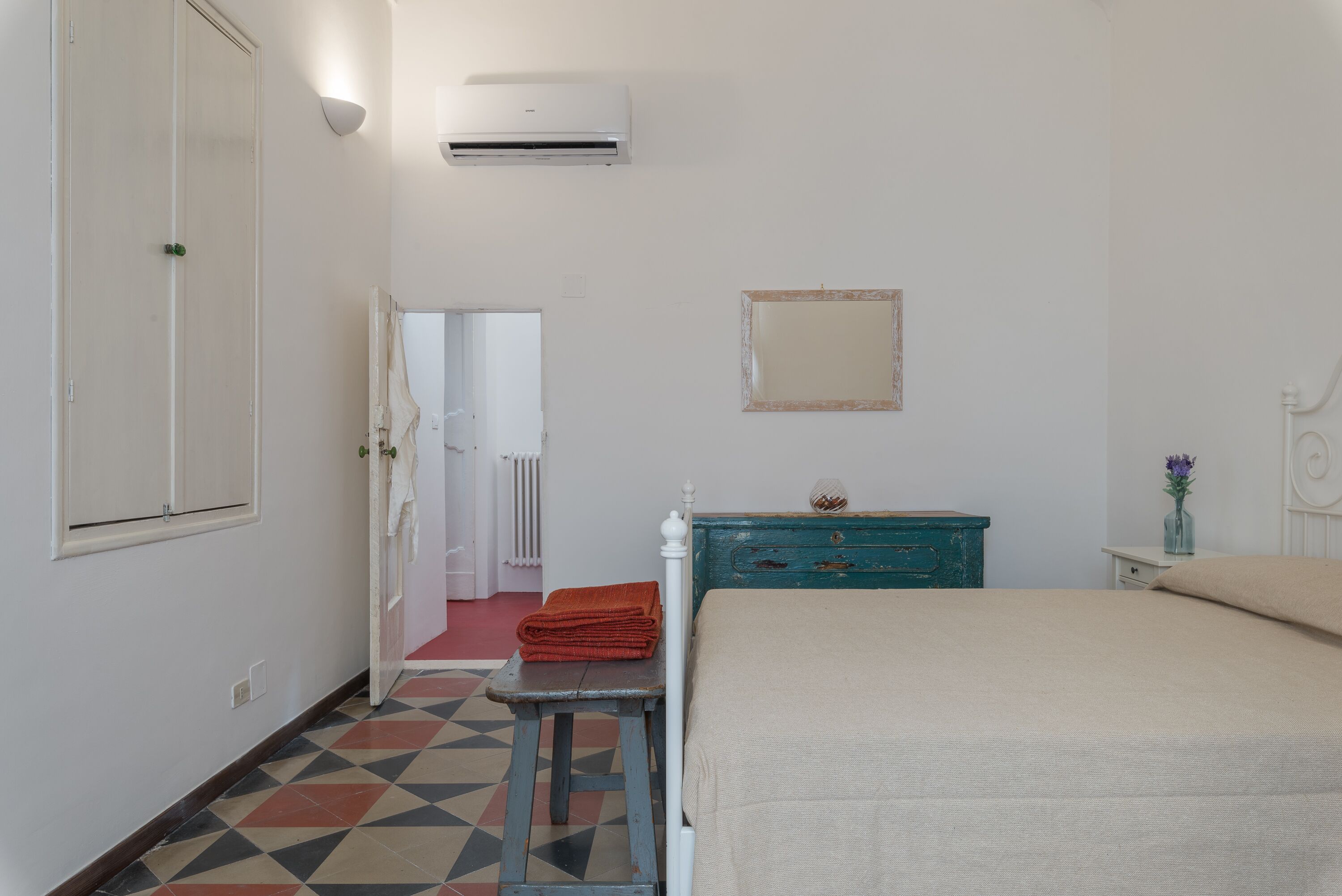 Une chambre à coucher avec un lit, une commode, un miroir et un radiateur.