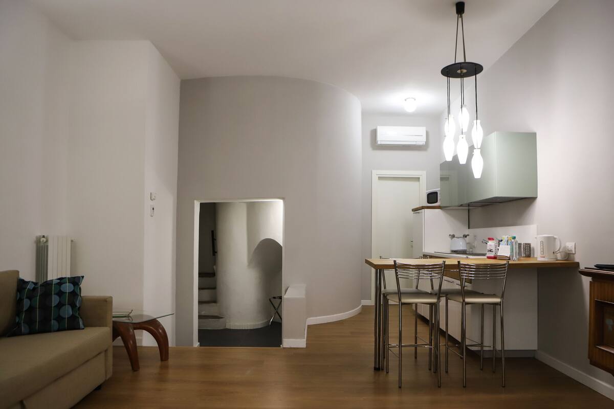 Een moderne keuken met een eethoek, een trap en een woonkamer met een bank en een salontafel.