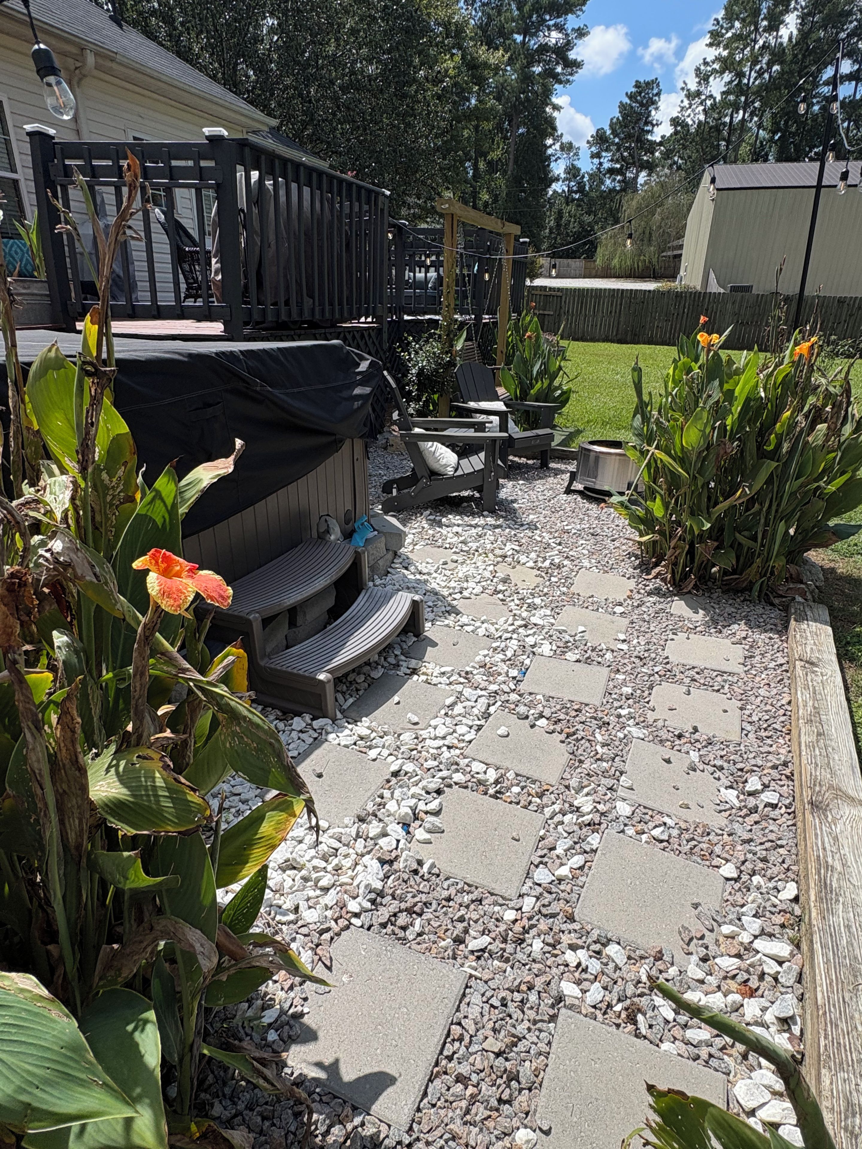 A patio area with a grill, seating, and a wooden deck.