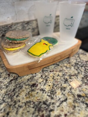 A wooden tray with a sandwich and a cookie on a granite countertop.