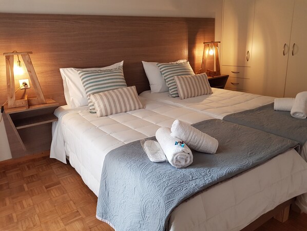 A double bed with two pillows, a bedside table with a lamp, and a wardrobe.