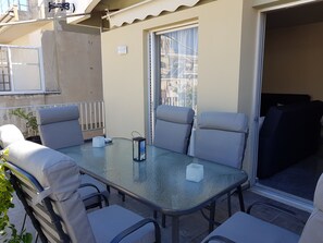 A glass-top table with six grey upholstered chairs, a small white container, and a lantern.