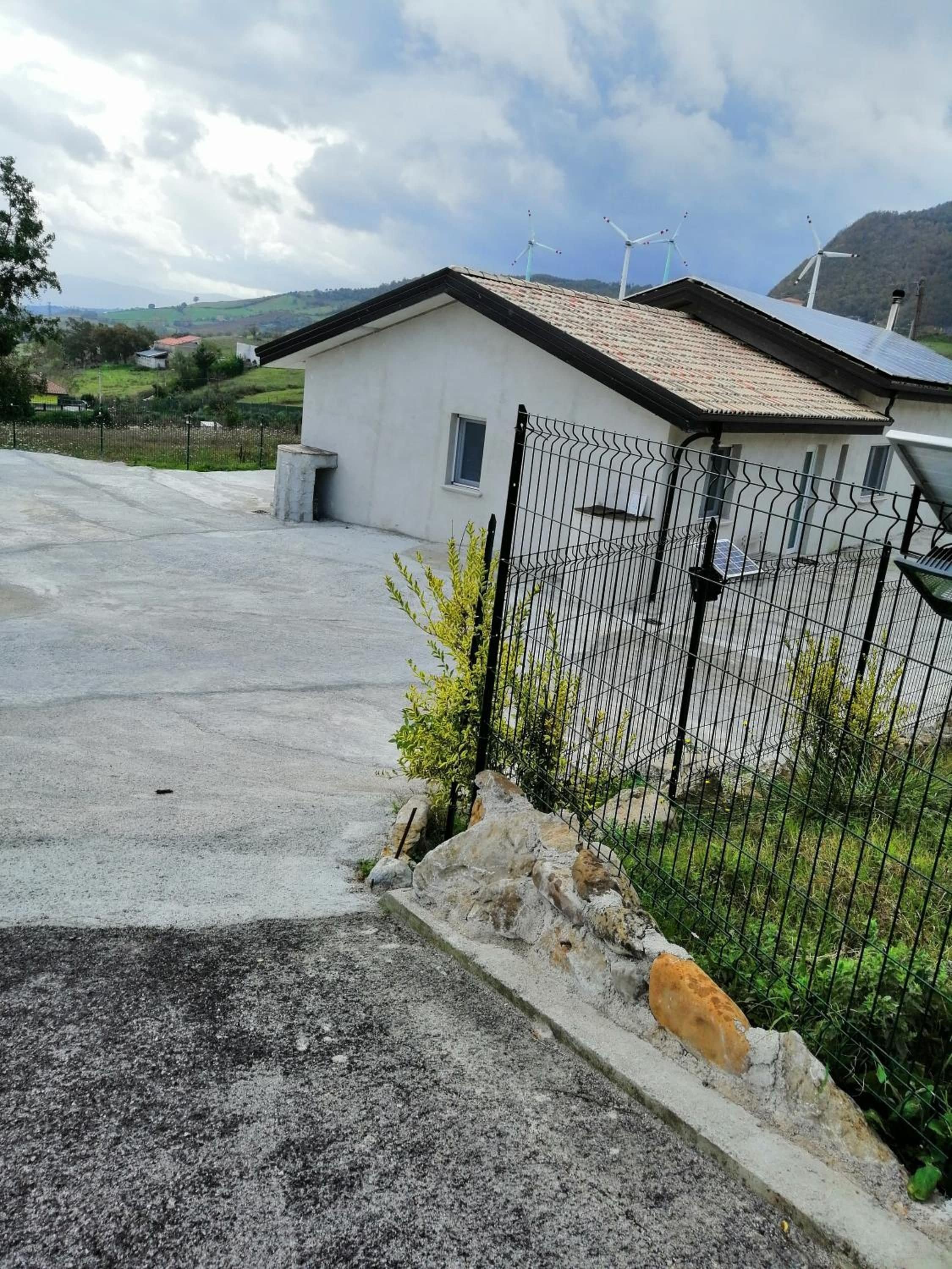 Un immobile residenziale con cortile recintato, una piccola casa con tetto spiovente e vista sul paesaggio circostante.