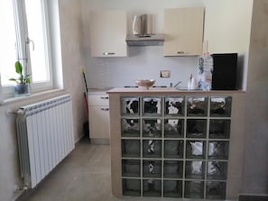 A kitchen with a central island, a built-in oven, and a window with a plant. - BeB Mezzanotte (Balvano)