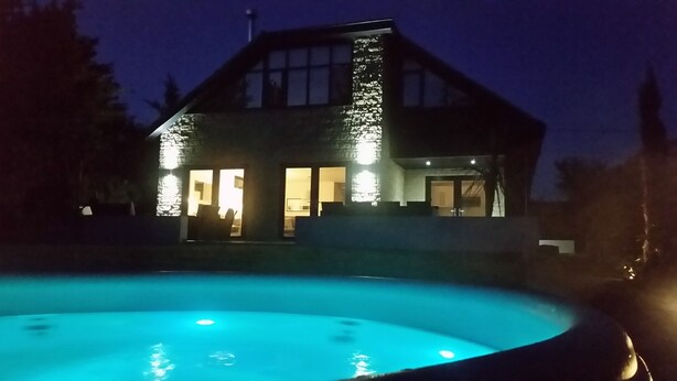 A house with a swimming pool at dusk. - Fantastic, sociable home in the beautiful village of Brighstone, with hot tub.  (Isle of Wight)