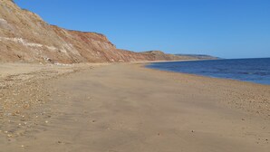 A sandy beach with cliffs and a clear blue sky. - Fantastic, sociable home in the beautiful village of Brighstone, with hot tub.  (Isle of Wight)