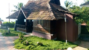 Ein traditionelles Holzhaus mit einem steilen Dach, umgeben von gepflegtem Rasen und kleinen Büschen.