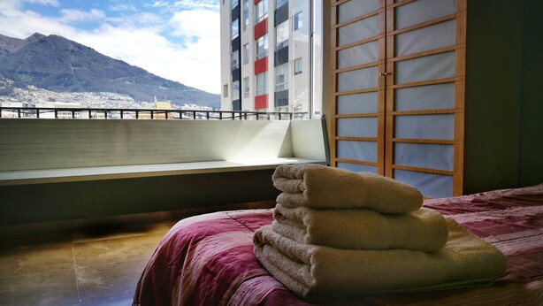 Ett hotellrum med en säng, ett fönster med utsikt över ett berg och en balkong.