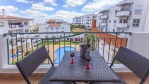 Un balcon avec une table, deux chaises et deux verres à vin.