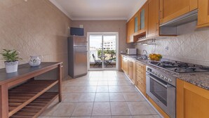 Une cuisine moderne avec des meubles en bois, un réfrigérateur en acier inoxydable, une cuisinière à gaz et un coin repas comprenant une table et des chaises.