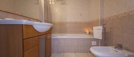 Un baño con bañera, bidé, lavabo y espejo.