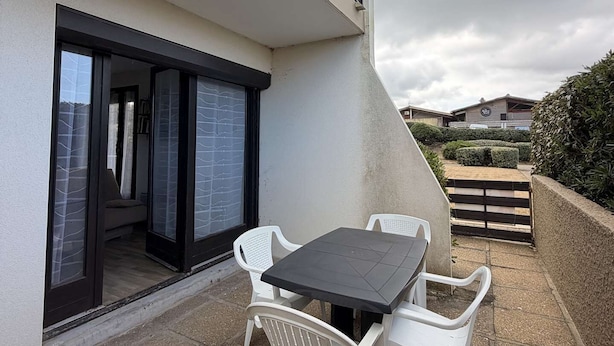 A modern outdoor patio with a table and chairs, a glass door entrance, and a view of the surrounding area. - Seignosse Ocean, apartment rated 2 stars, right next to Penon beach (SEIGNOSSE)