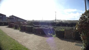 A paved pathway with a wooden fence and dense shrubbery. - Seignosse Ocean, apartment rated 2 stars, right next to Penon beach (SEIGNOSSE)