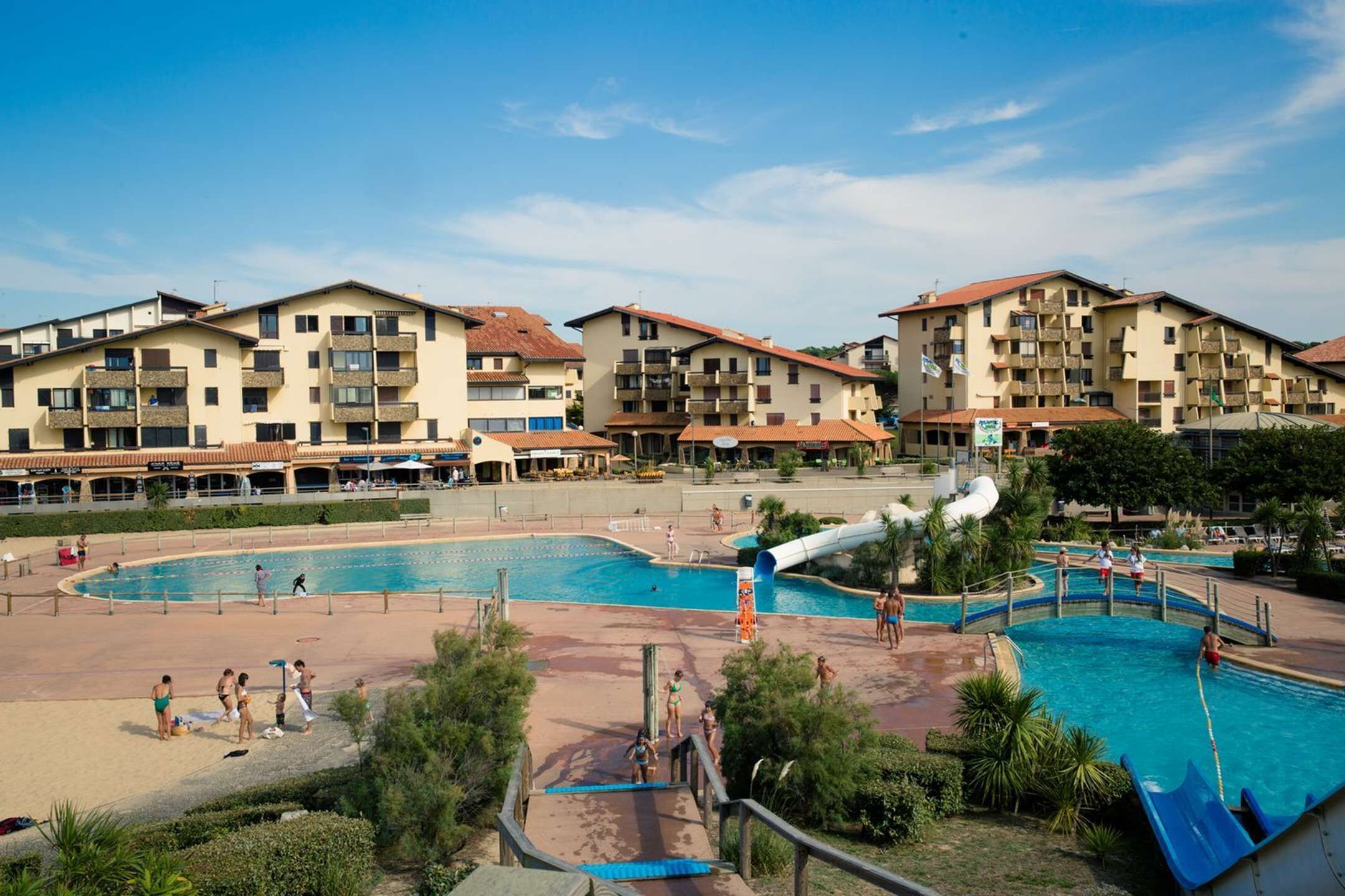 A resort with multiple swimming pools, a water slide, and a beach area.