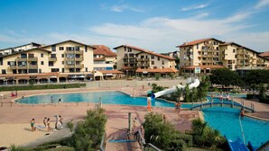 A resort with multiple swimming pools, a water slide, and a beach area.