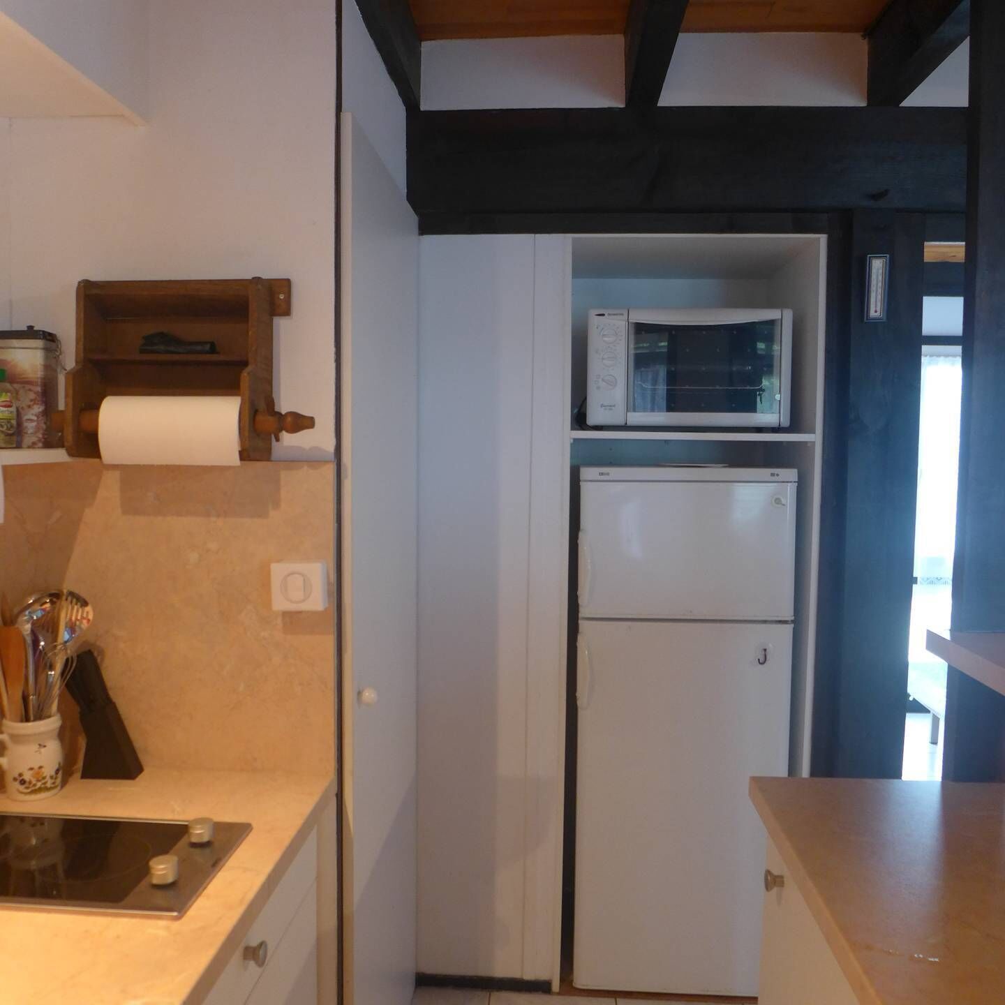 A compact kitchen with a microwave, a refrigerator, and a roll of paper towels on the counter.