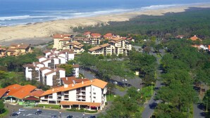 A coastal resort with multiple-story buildings, a parking area, and a view of the beach and ocean.