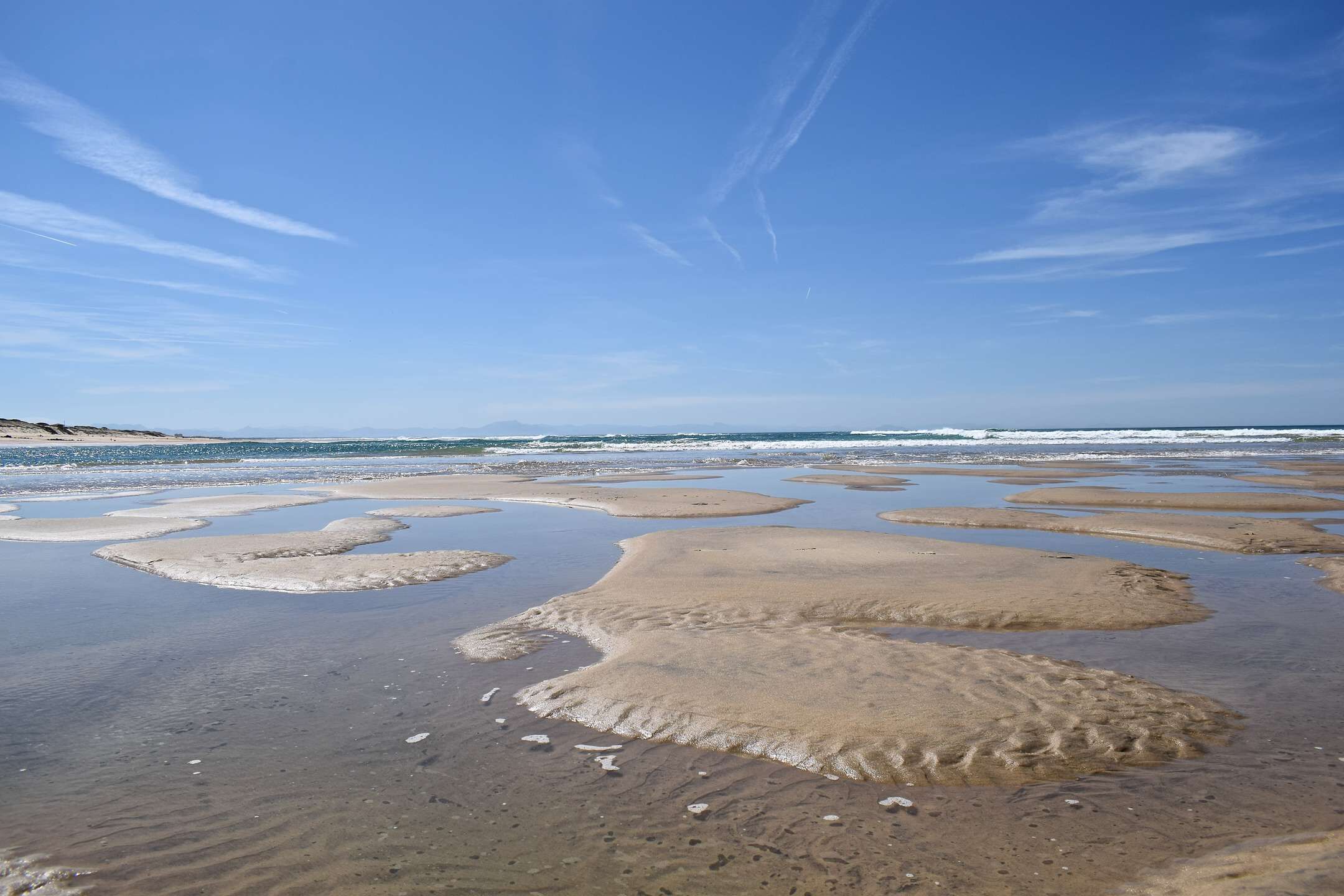 A beach with wet sand and water channels.