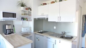 A compact kitchen with white cabinets, a microwave, a coffee maker, and a small refrigerator. - Seignosse Ocean, 1-star apartment, direct access to the ocean and private parking space, sleeps 4 (SEIGNOSSE)
