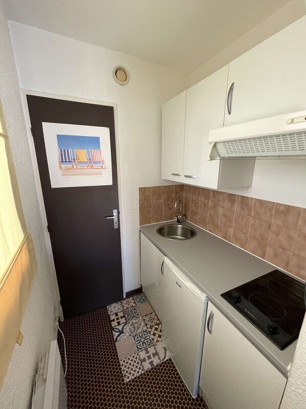 A compact kitchen with a sink, stove, and white cabinets. - Seignosse Océan, spacious and bright studio, walking distance to the beach, ideal for 2 people (SEIGNOSSE)