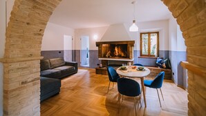 A cozy living area with a fireplace, a dining table with chairs, and a sofa. - Villa de Castelletta (Rapagnano)