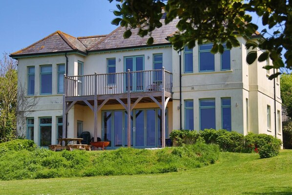 A two-story house with a balcony, a lawn, and a garden.