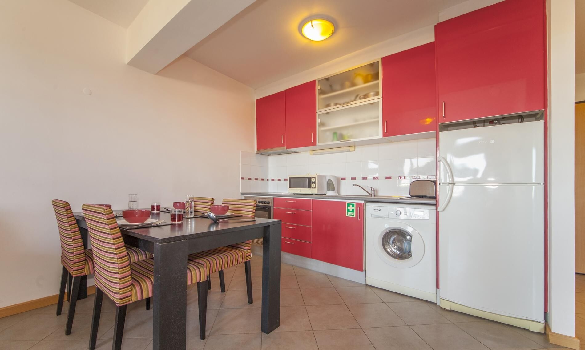 Una cocina compacta con comedor, lavadora y refrigerador.