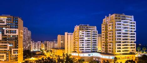 A high-rise residential building complex at night with multiple balconies and illuminated windows.