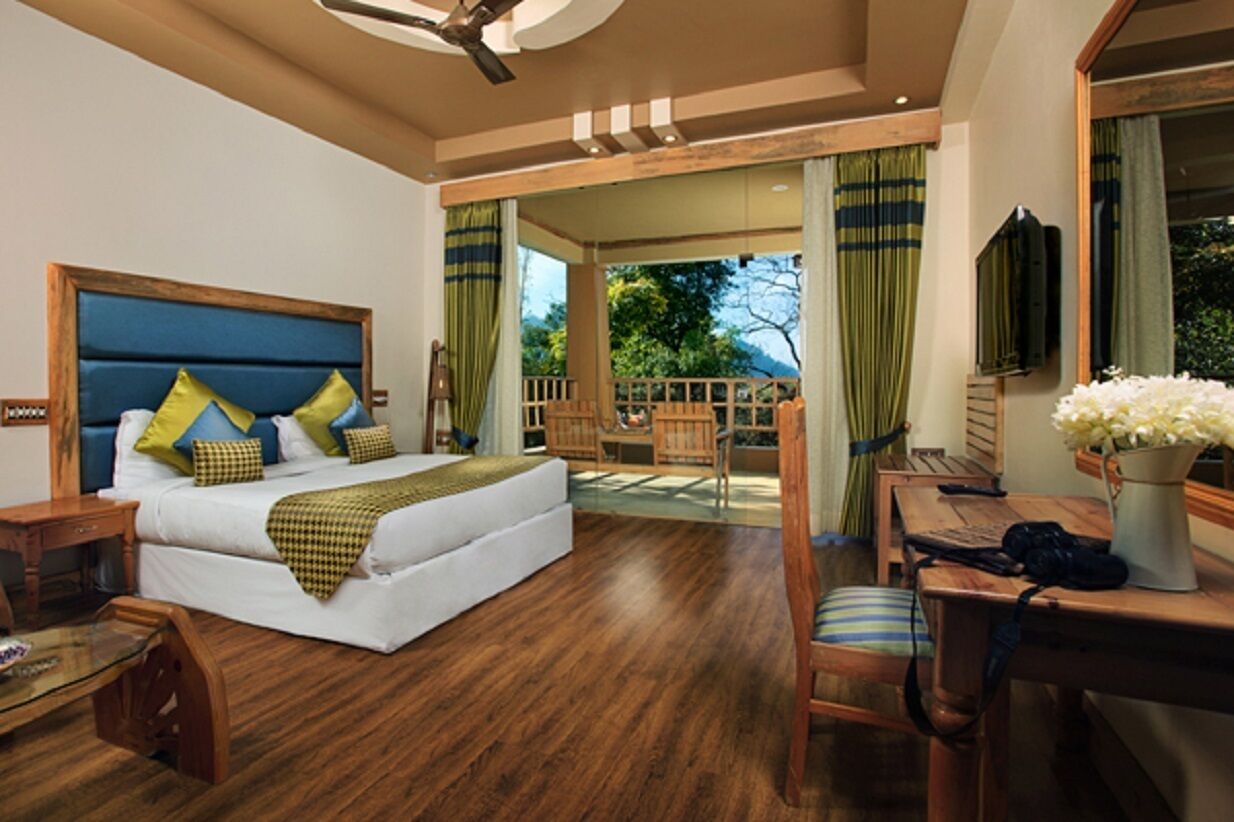A bedroom with a large bed, a wooden desk, and a view of the outdoors.