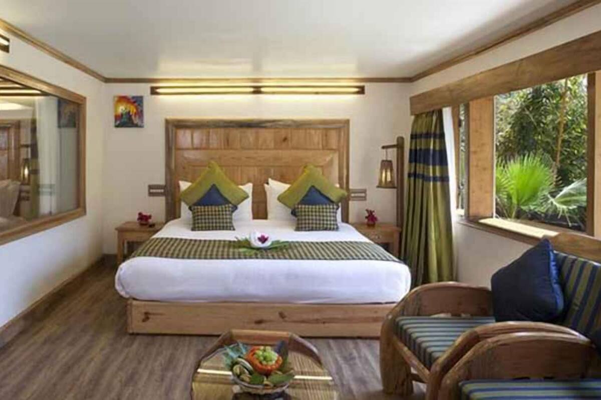 Une chambre à coucher avec un lit en bois, un grand miroir, une table de chevet, une chaise et une fenêtre avec des rideaux.